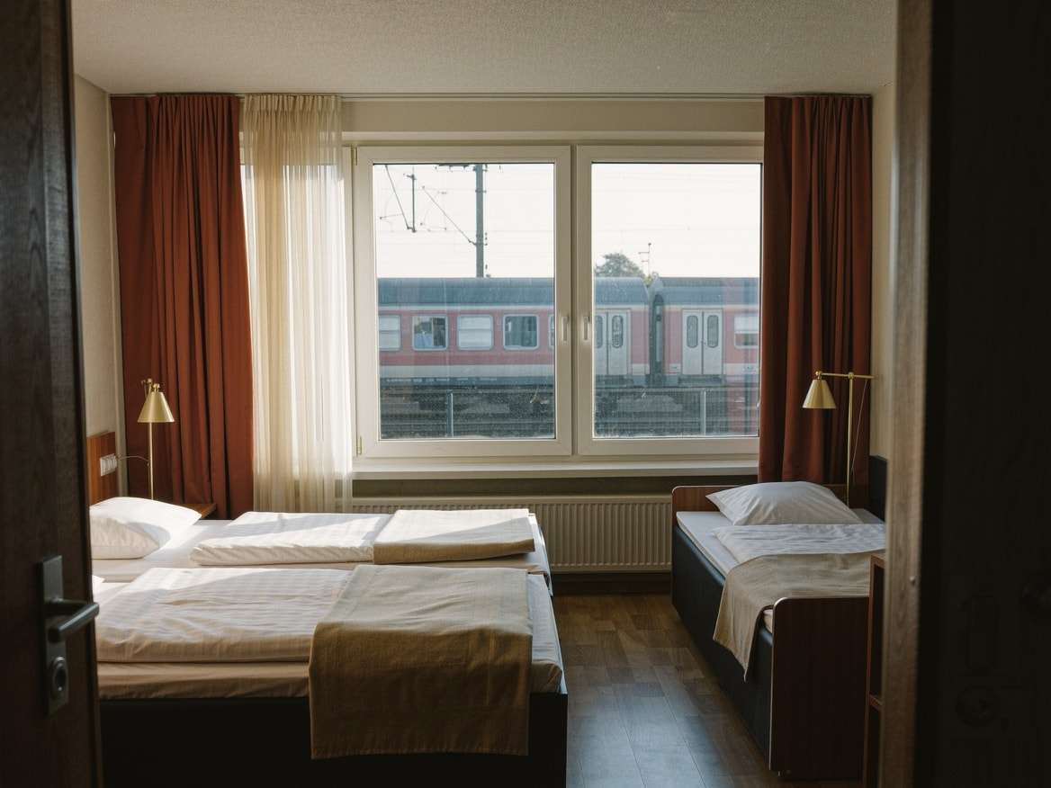 Familienzimmer: Doppelbett und separates Einzelbett unter einem breiten Fenster, heller Holzboden, zwei Leselampen