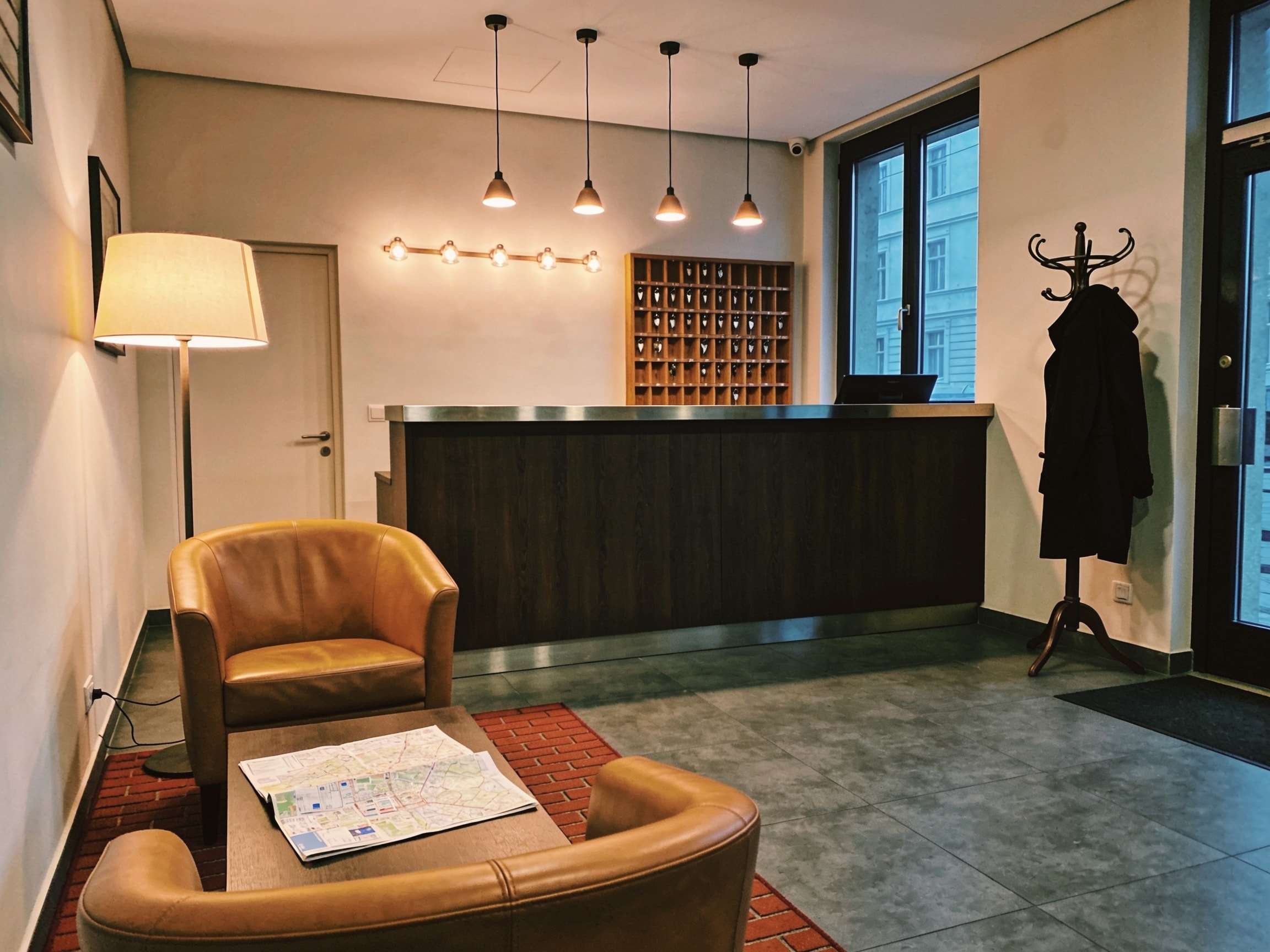 Lobby mit Ledersesseln, rotem Teppich und einer Stehlampe, im Hintergrund die Rezeption